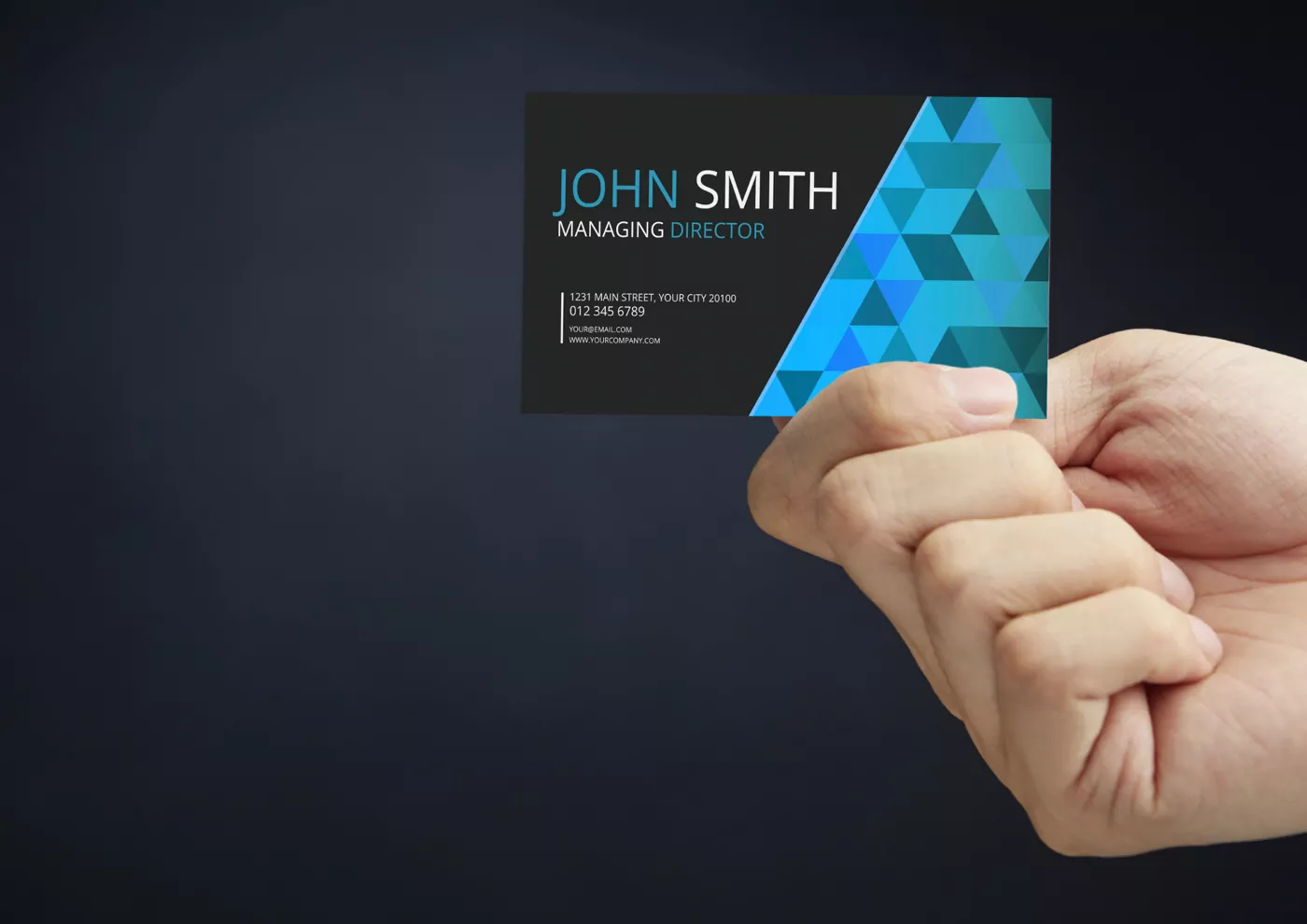 A printed business card held up between finger and thumb